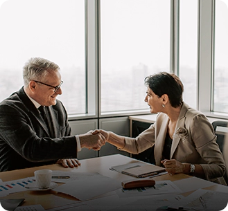 Two people shaking hands over a table.