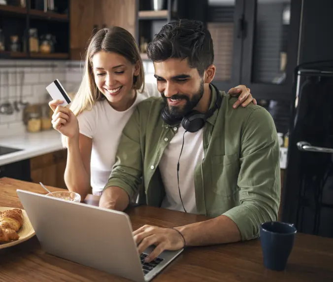 A man and woman sitting at a table with a laptop.