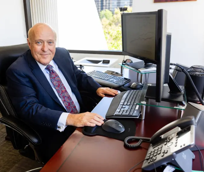 A man sitting at his desk in front of two computers.