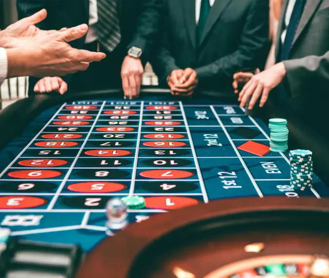 A group of people standing around a roulette table.