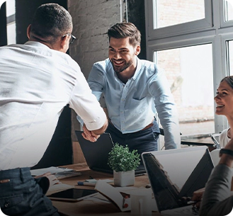 A group of people sitting around a table shaking hands.