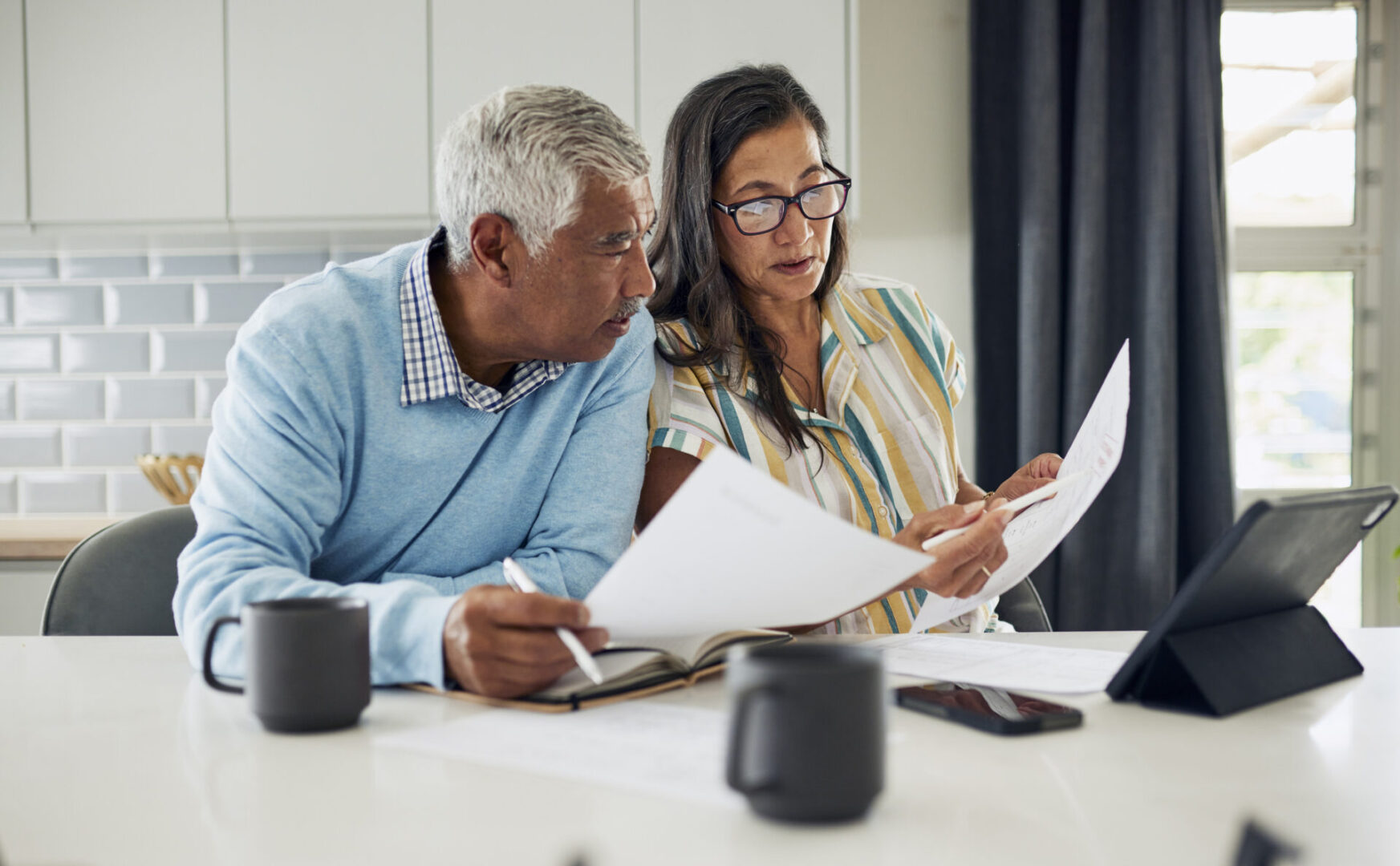 A man and woman looking at papers on the table.