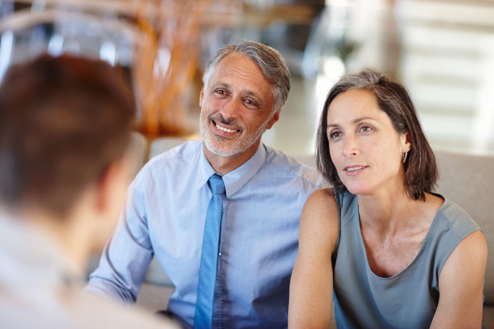 A man and woman sitting at a table with another person.